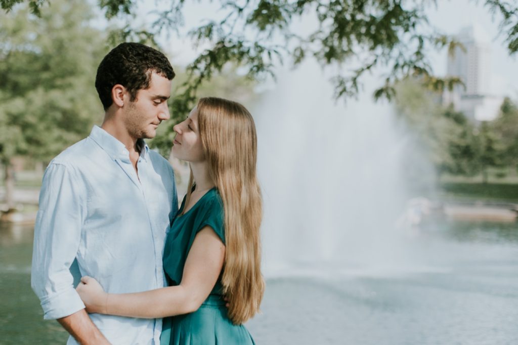 man and woman stand in front of fountain on the indy canal walk, one of the Best Indianapolis Engagement Photo Locations