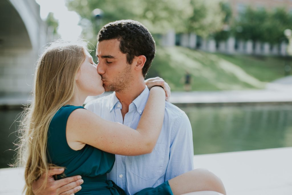 man holds woman in arms and kisses her on indy canal walk, one of the Best Indianapolis Engagement Photo Locations