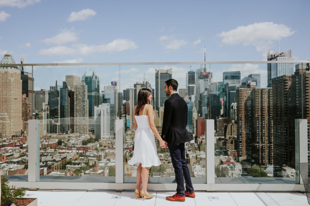 new york skyline splayed out behind couple at their New York Rooftop Engagement session