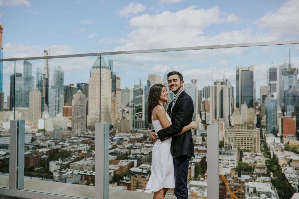 Manhattan skyline visible behind couple at their New York Rooftop Engagement session