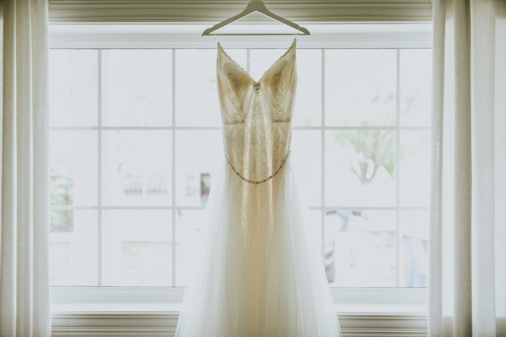 such beautiful symmetry with a wedding dress hung in a window and backlit by the sun at this norris estate wedding