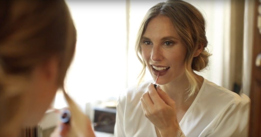 blonde woman does makeup in a mirror during this benton house wedding film