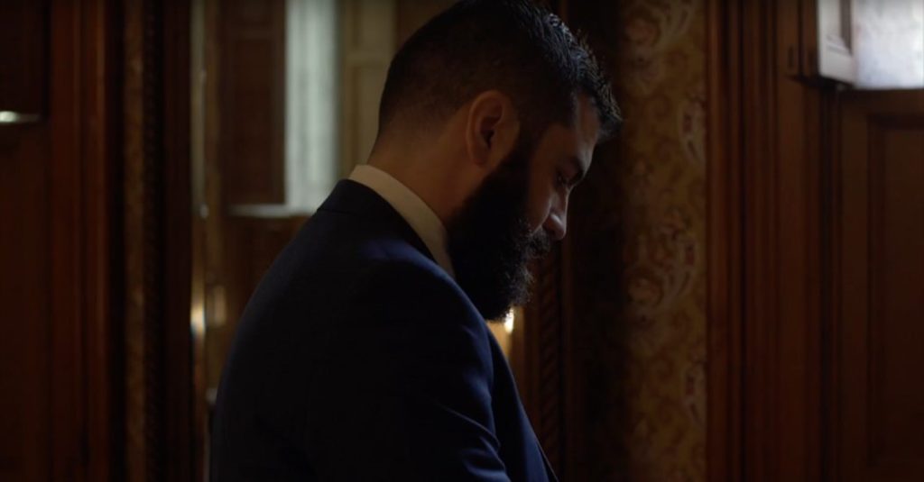 man dresses in dark room during this benton house wedding film