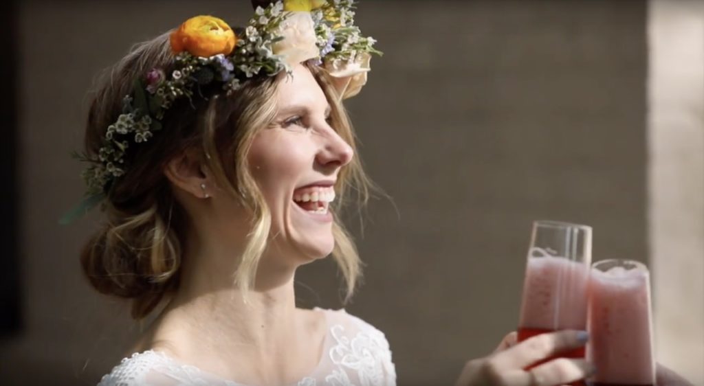 woman with floral crown laughs while drinking sparkling beer during her benton house wedding film