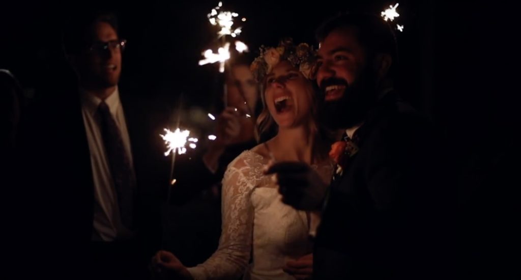 bride and groom laugh while watching sparklers burn