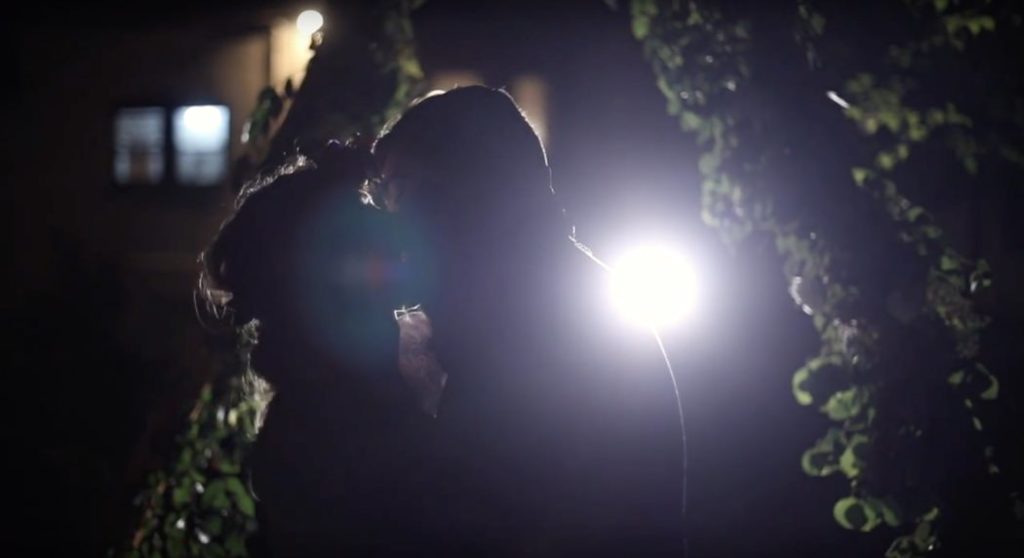 bride and groom kiss at night while backlit with flare during their benton house wedding film
