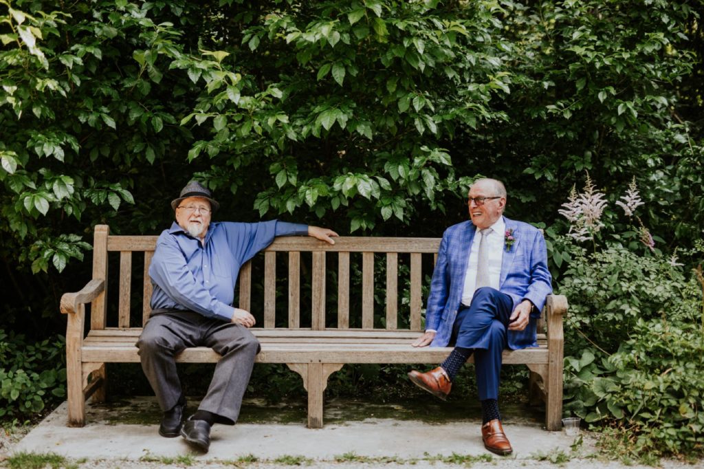 grandparents of bride and groom sit on wooden bench in newfields during an IMA wedding