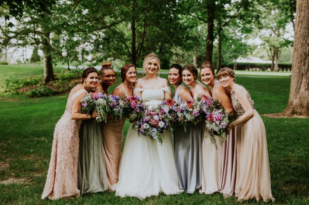 bride and bridesmaids hold flowers at newfields
