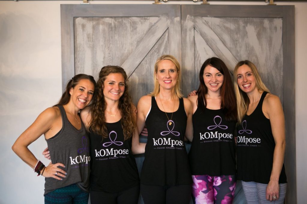 Kompose Yoga instructors in front of a wooden door
