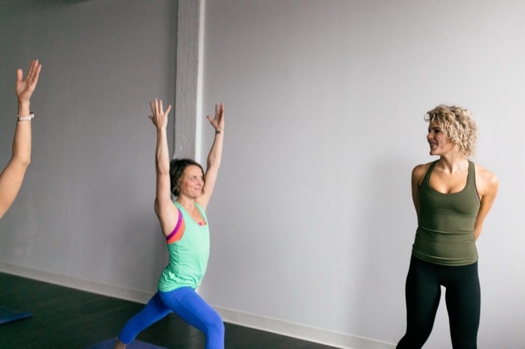 blonde woman with curly hair and green tanktop watches other women do yoga during an Indianapolis Yoga Photography shoot