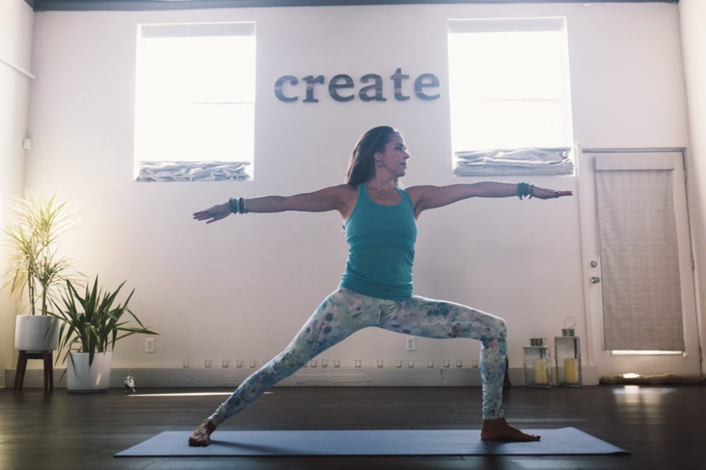 woman does warrior pose in front of word create during an Indianapolis Yoga Photography shoot
