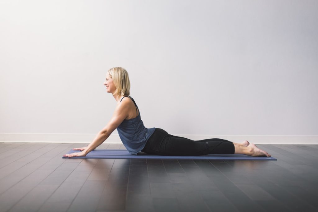 blonde woman stretches stomach muscles on a yoga mat