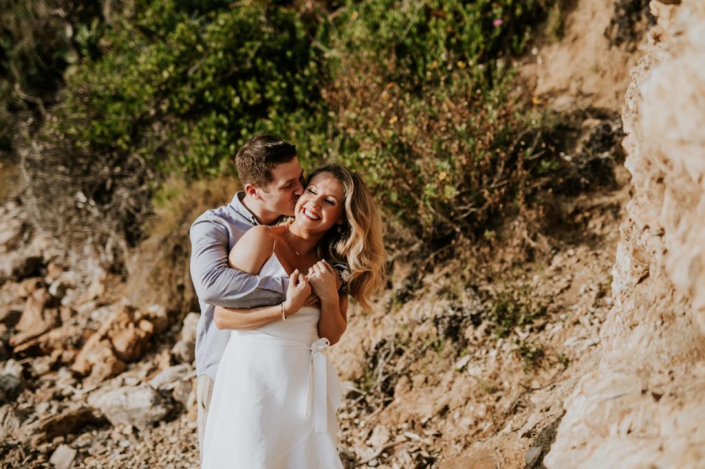 man kisses woman at little corona del mar beach during laguna beach engagement shoot