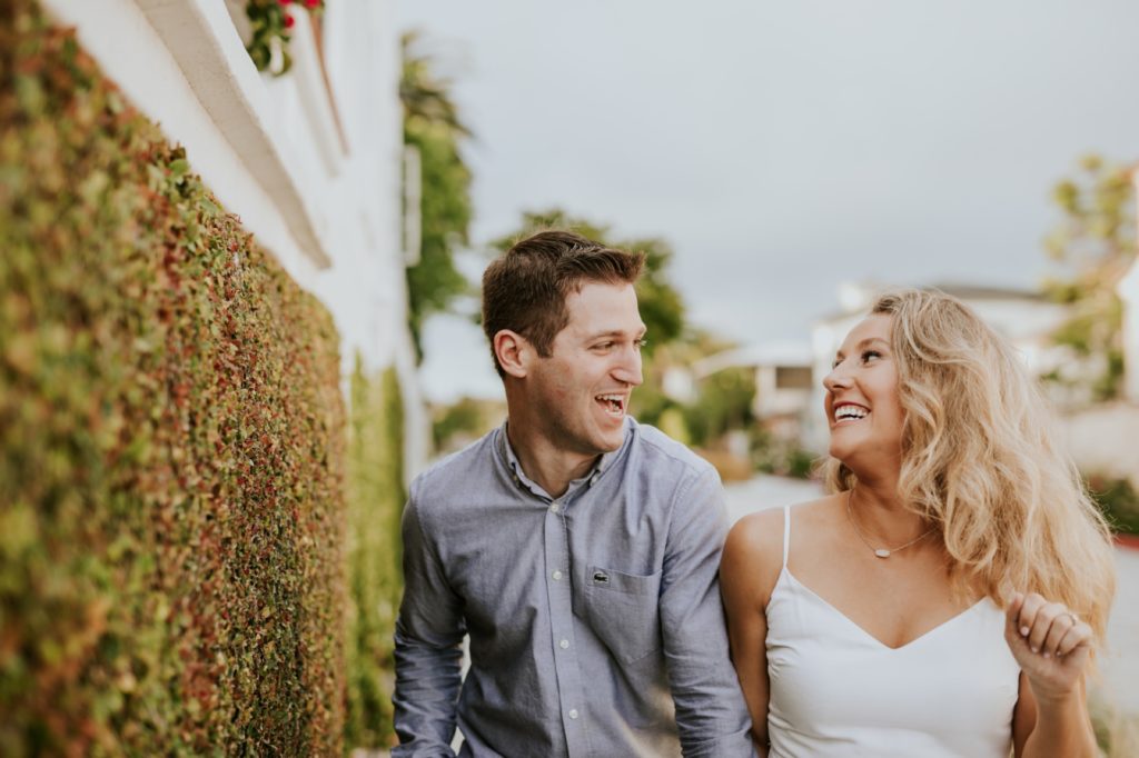 man and woman walk and hold hands during their corona del mar engagement shoot