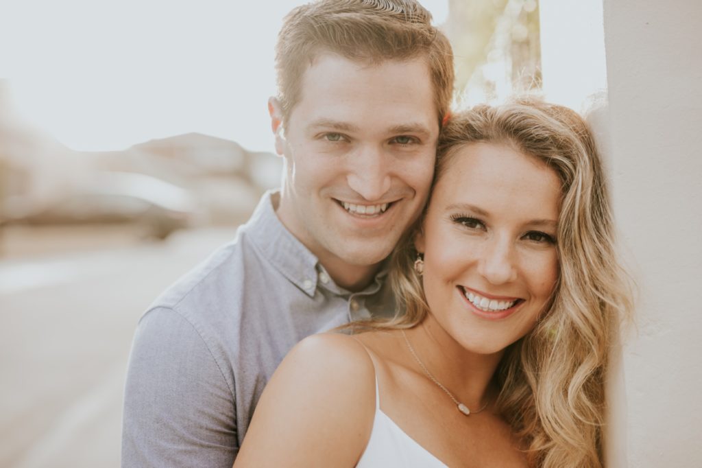 man and woman cuddle while backlit by sun during their corona del mar engagement shoot