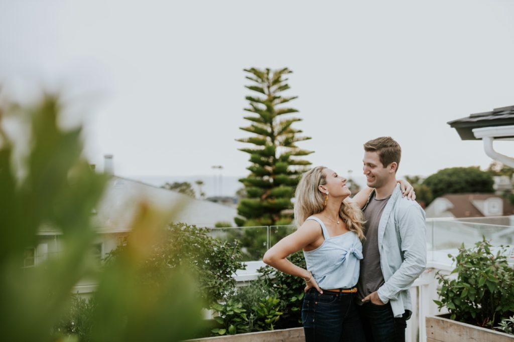 blonde woman looks up at man with sass during their laguna beach engagement shoot at hotel joaquin