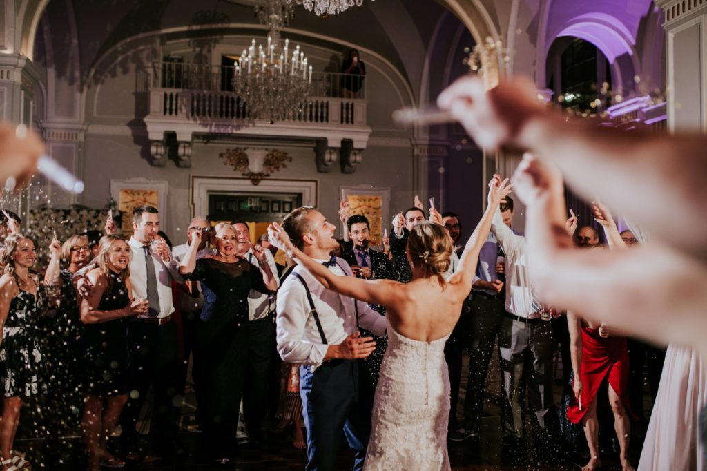 bride and groom laugh and dance while surrounded by people throwing glitter at their Omni Severin Wedding