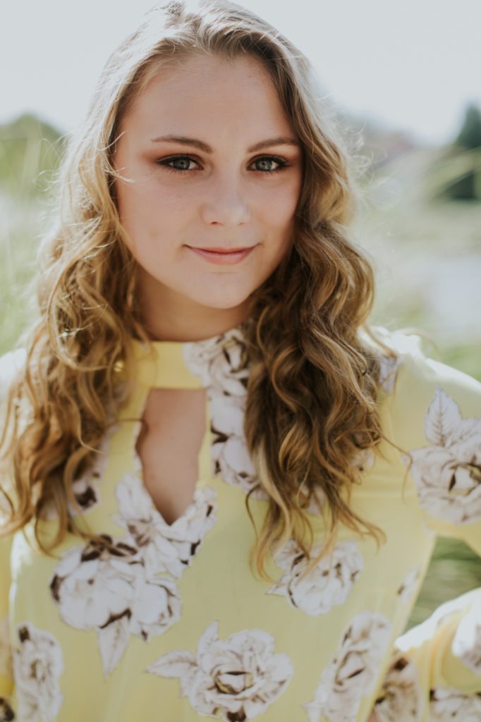 girl in yellow floral dress smiles at camera in Muncie Indiana Senior Photography