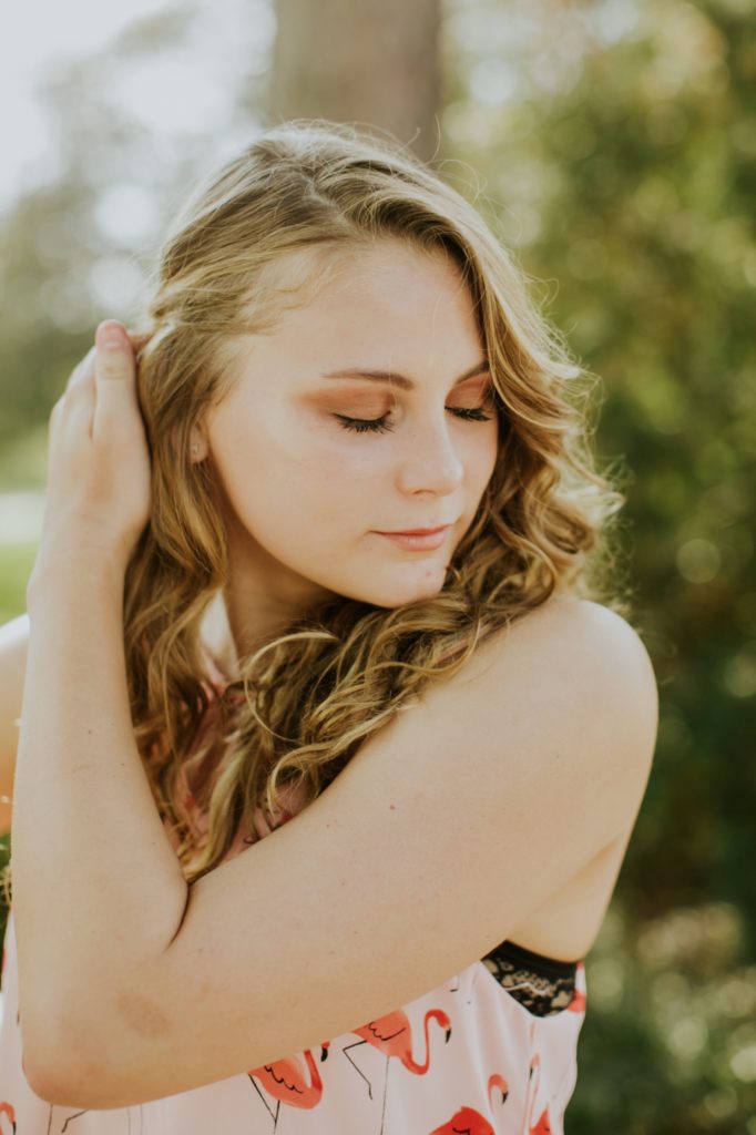 blonde girl brushes hair out of her face in this Carmel Senior Portraits session