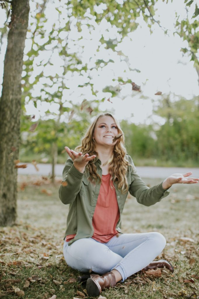 girl in green jacket watches leaves fall in her Carmel Senior Photos