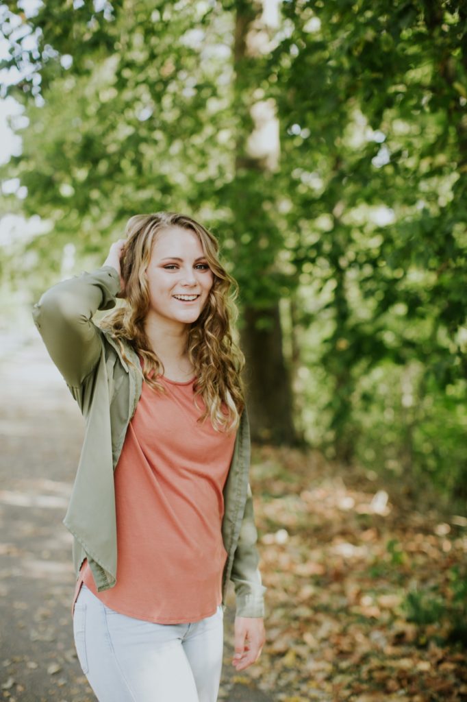 girl messes with her hair in the woods in Zionsville Senior Photo session