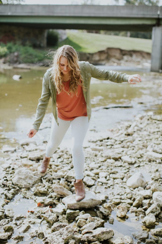 girl balances herself on rocks in heels in creek bed in Muncie Indiana Senior Portraits