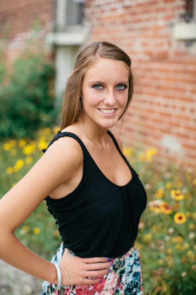 girl in black tank top with hand on hip in front of flowers in Noblesville portraits