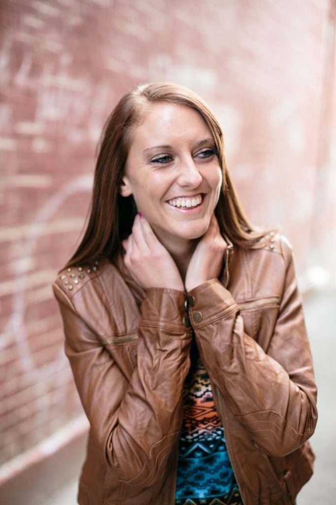 girl in leather jacket laughs in letterman's alley in muncie senior pictures