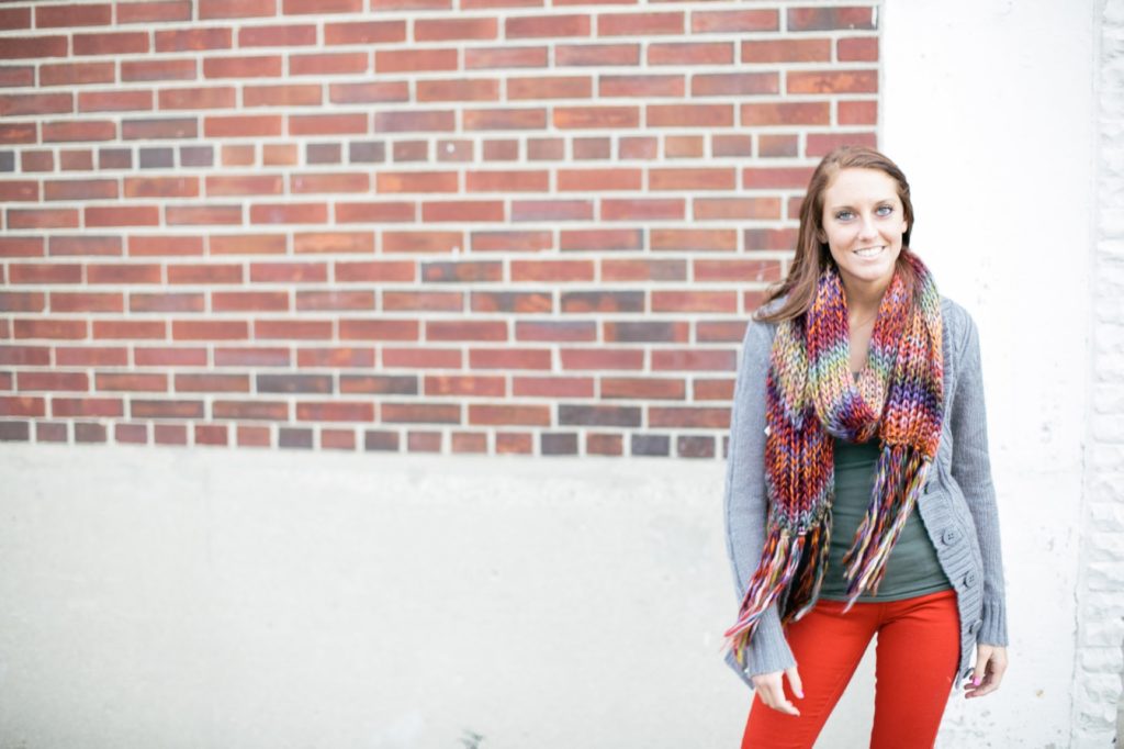 girl with scarf stands in front of brick wall for muncie senior pictures
