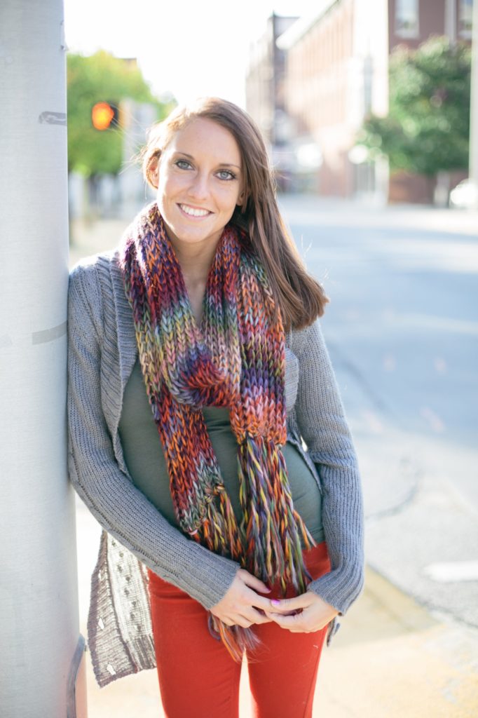 girl in scarf leans against traffic light pole in muncie senior pictures