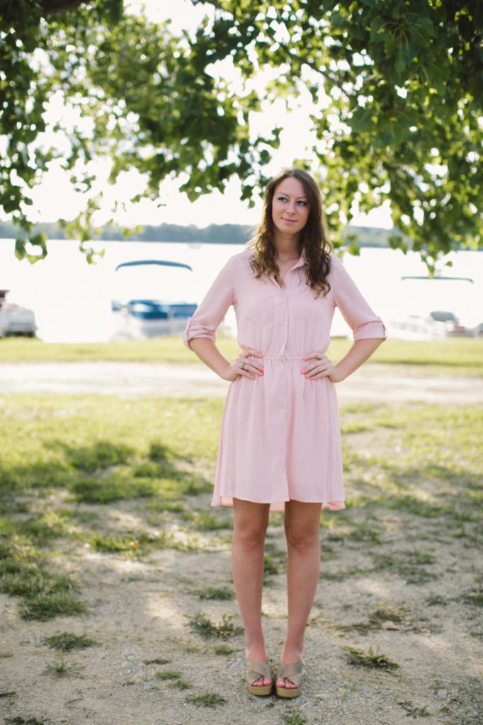 girl in pink dress with hands on hips in shade in front of boats in Muncie senior portraits