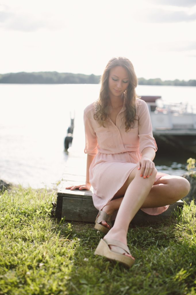 girl in pink dress sits on dock at Prairie Creek Reservoir in Delaware County Portraits