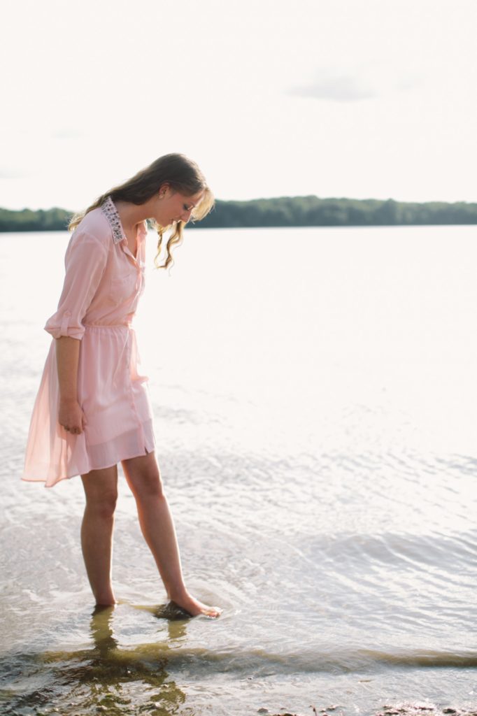 Girl in Pink dress walks through water at prairie creek reservoir in Muncie senior portraits