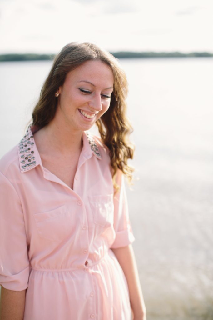 girl in pink dress smiling and looking down humbly in Muncie senior portraits