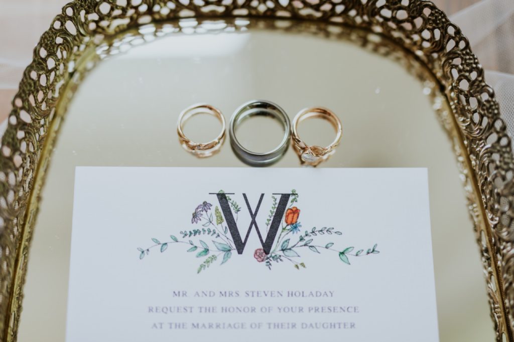 rings on a mirror for a wedding with a paper invitation