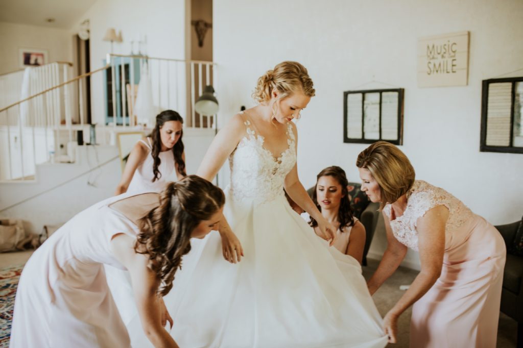 bride is surrounded by bridesmaids and mothers as they help her dress for her muncie wedding photography