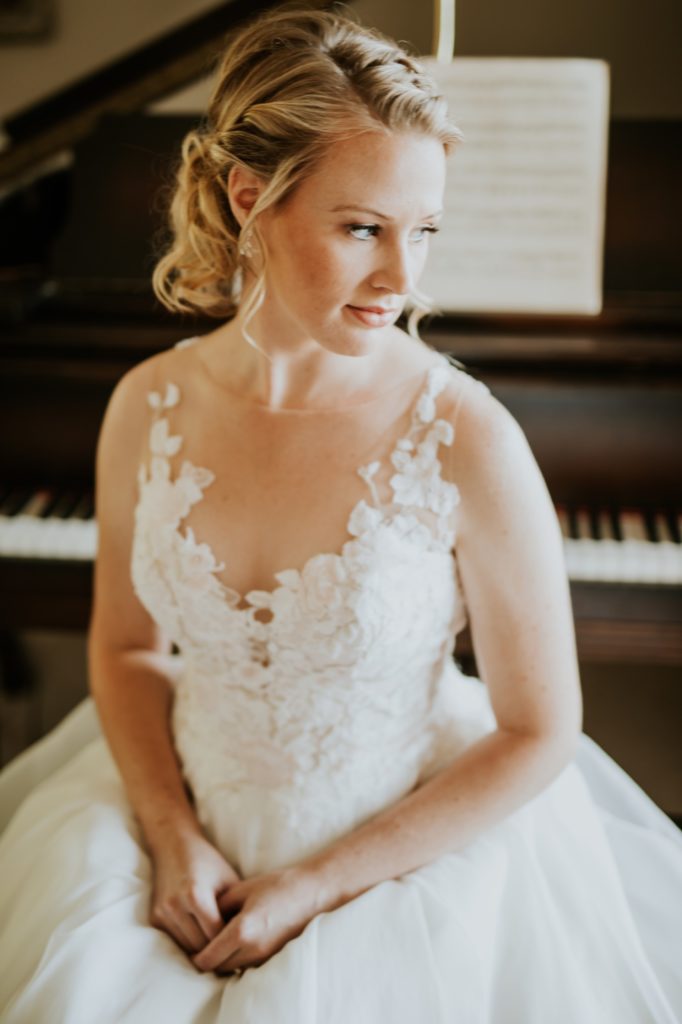 bride sitting in front of a piano for her muncie wedding photography