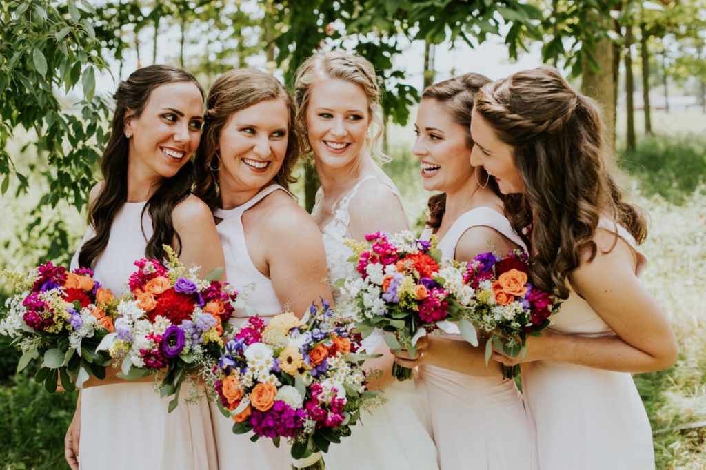 bride and bridesmaids in a line and bunched together with flowers for muncie wedding photography