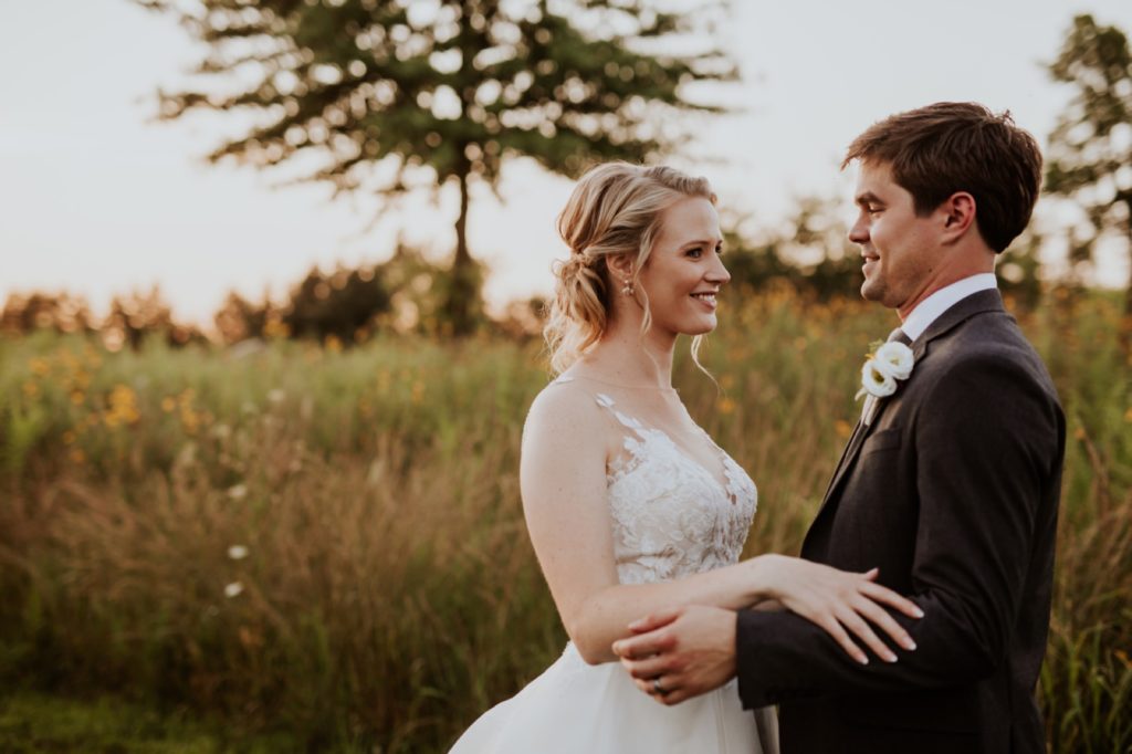 bride and groom hold hands and look into each other's eyes during their muncie wedding photography