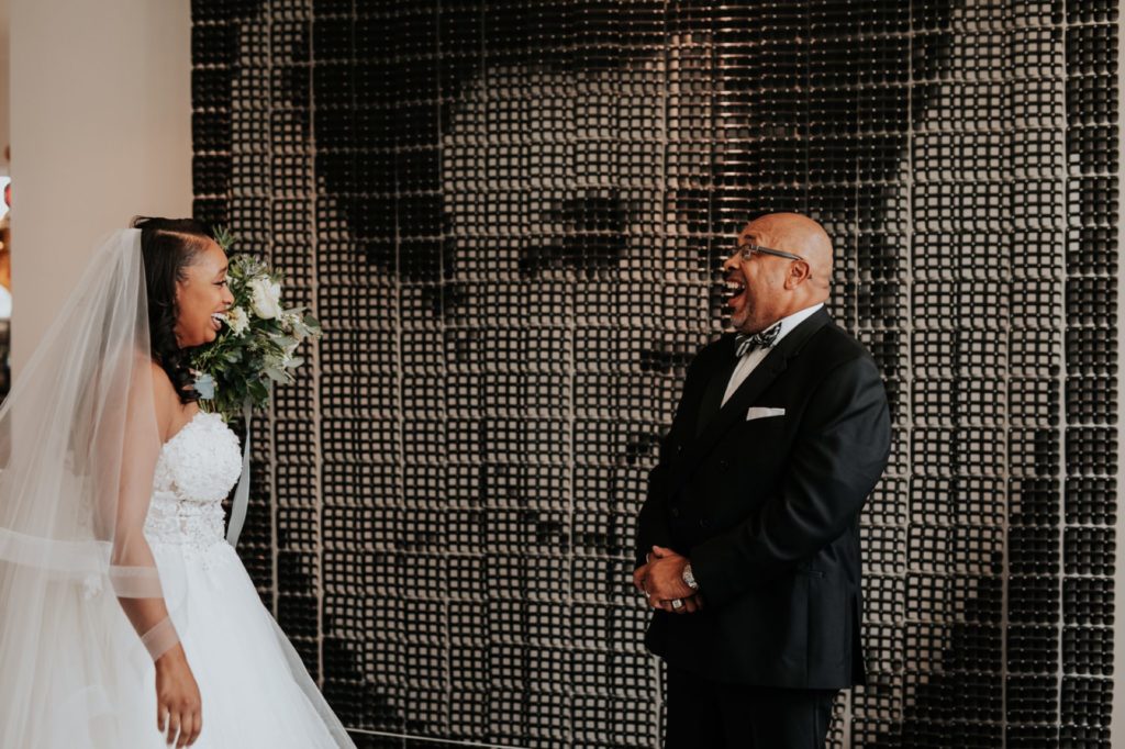 father of bride smiles and gasps as he sees his daughter for first time on wedding day in alexander hotel in downtown indy