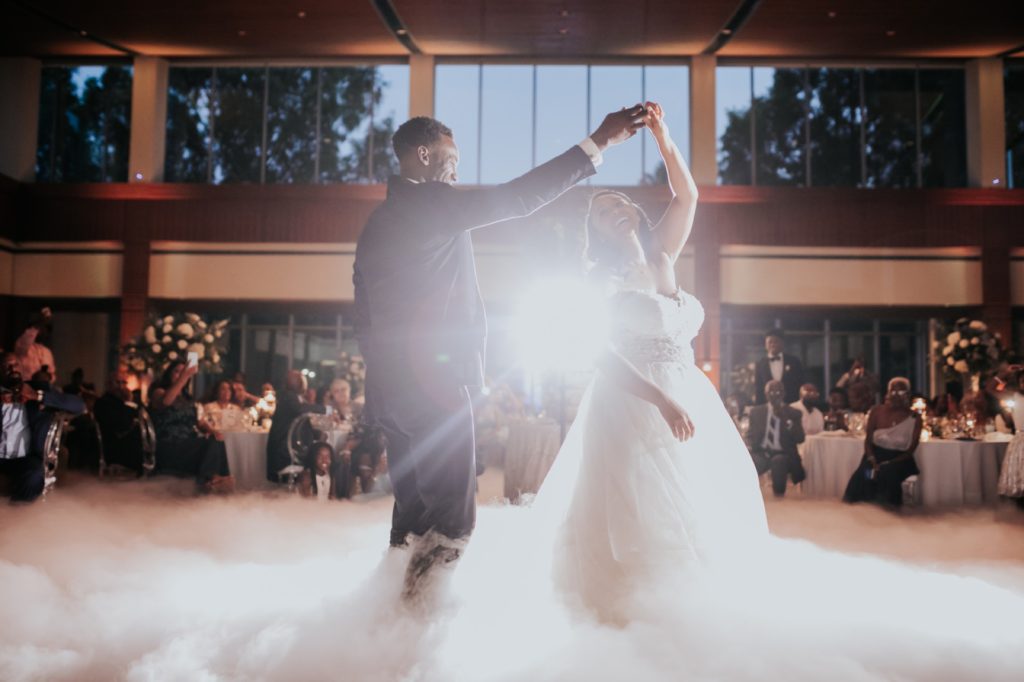 groom spins bride on cloudy dance floor backlit by off camera flash during newfields wedding