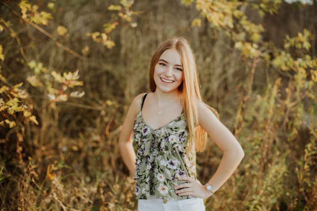 Girl in floral tank top with hands on her hips smiling in Zionsville portraits