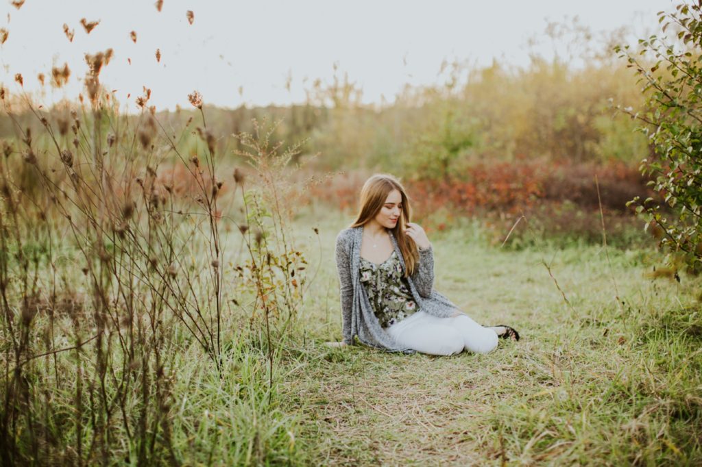 girl sitting in field in autumn at sunset for Noblesville Senior Photos