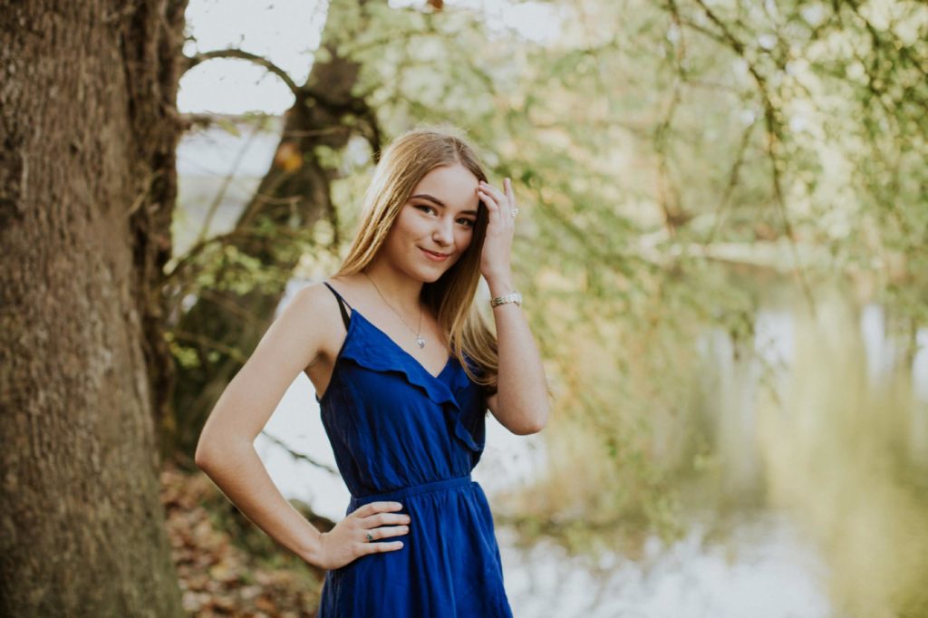 girl in blue dress next to water in front of trees for Noblesville Senior Portraits