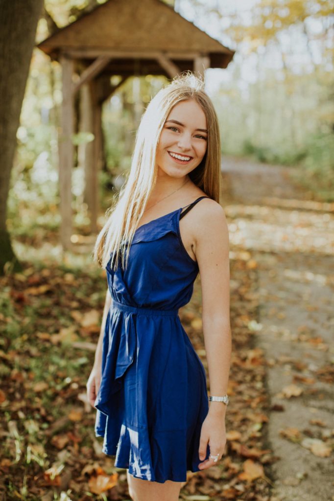 girl in blue dress in woods with light behind her for Westfield Photos