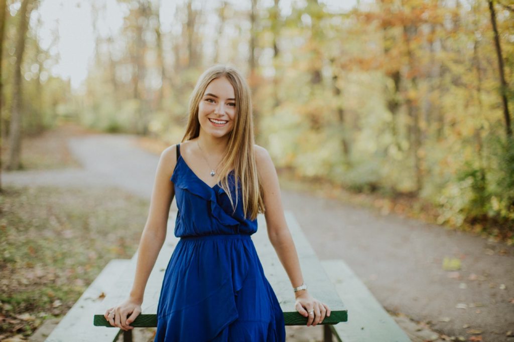Girl in blue dress on picnic bench during fall for Noblesville Senior Portraits