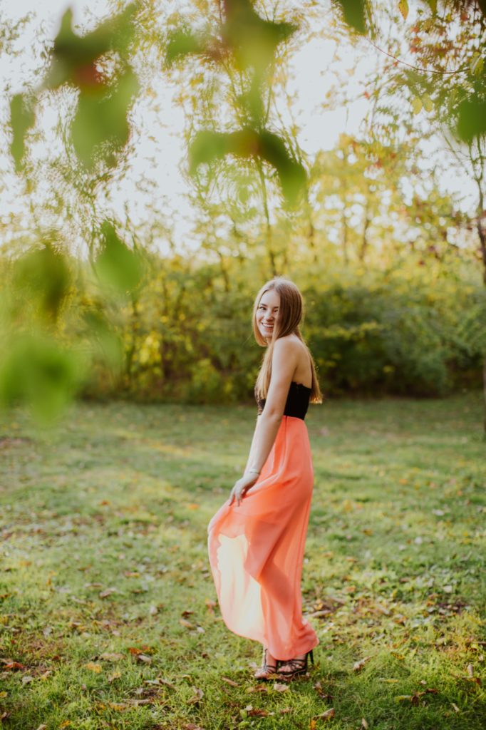 Girl in Pink dress in field framed by leaves for Noblesville Senior Portraits
