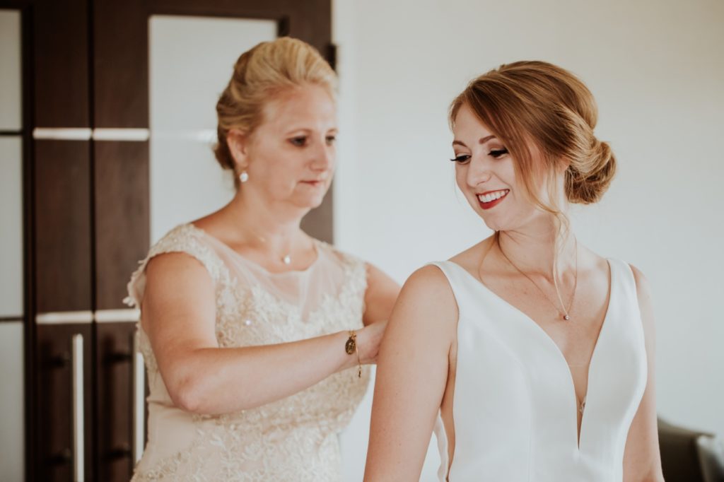 mother of the bride helps her daughter into her wedding dress