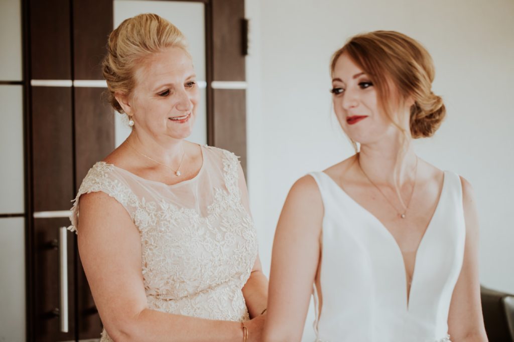 mother of the bride buttons up wedding dress of daughter