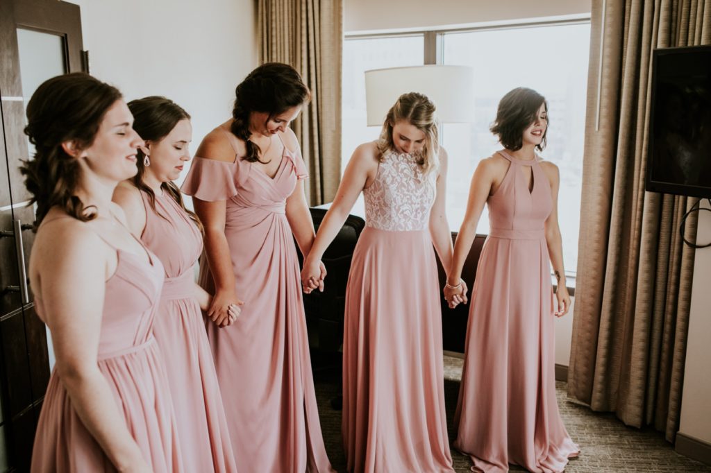 bridesmaids in pink dresses lined up to see bride for the first time in wedding dress for a Tinker House Wedding